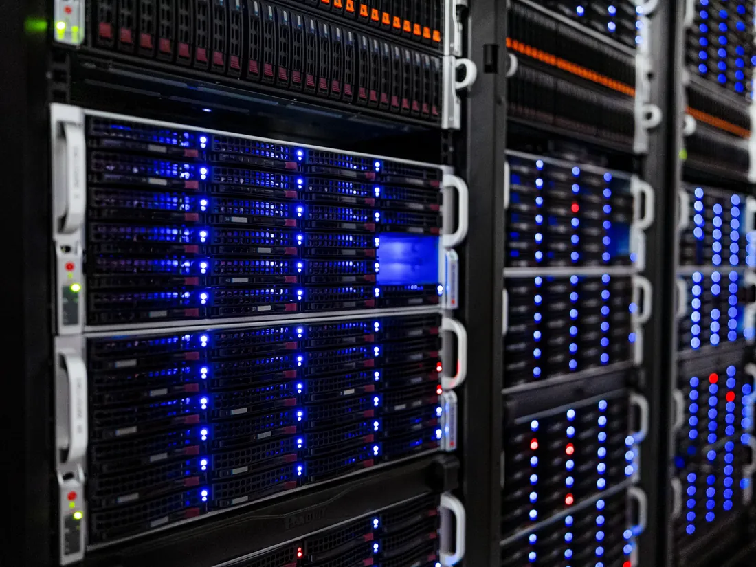 Deretan rak server dengan lampu indikator biru di ruang data center