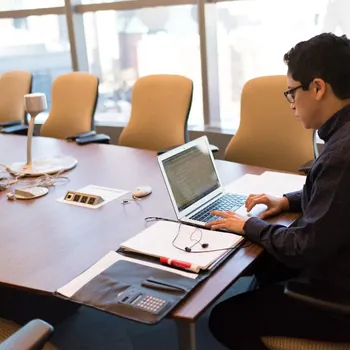 Orang sedang bekerja dengan laptop di ruang kerja kantor saat survey lokasi